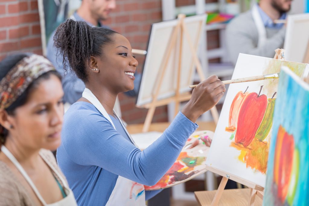 Two women painting in a group art class.