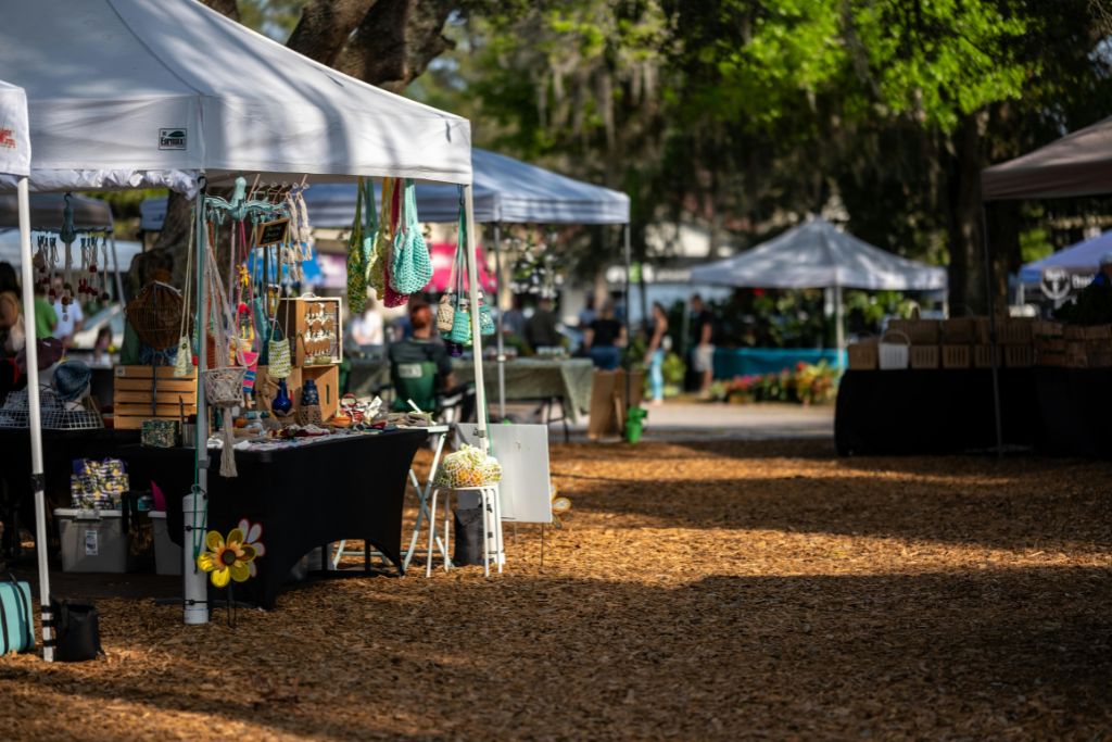 Market stalls covered by awnings along a wood bark pathway.