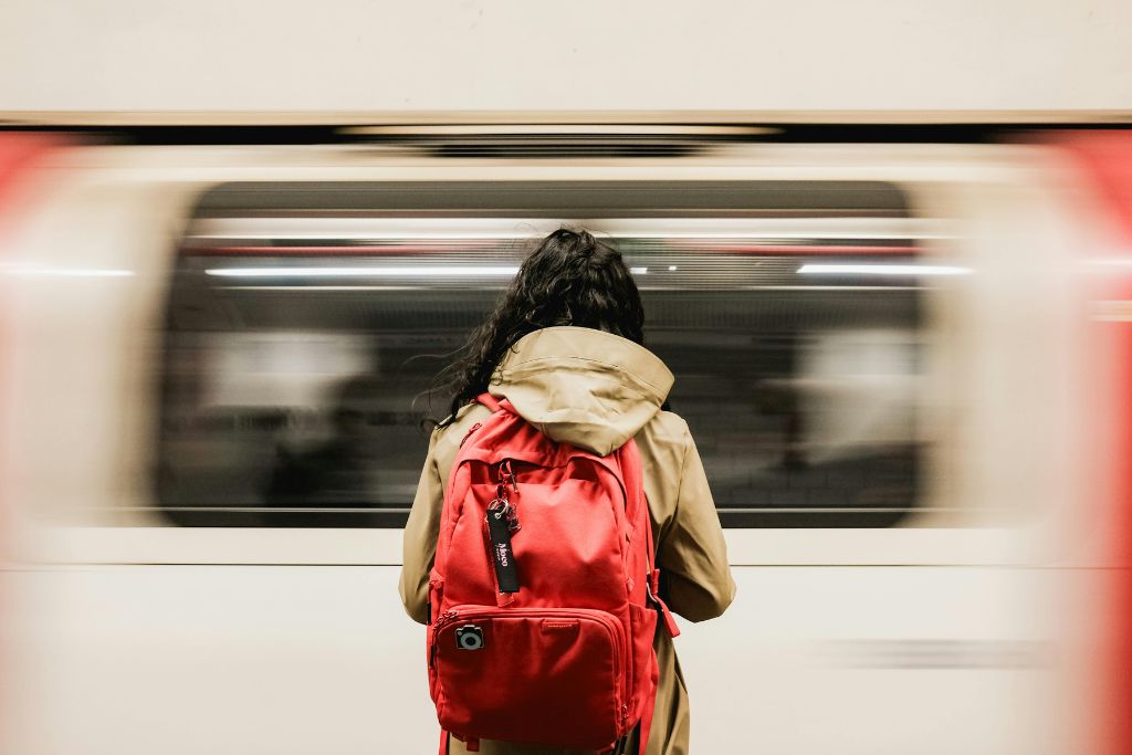 A woman stands on a London tube platform as a train speeds by.