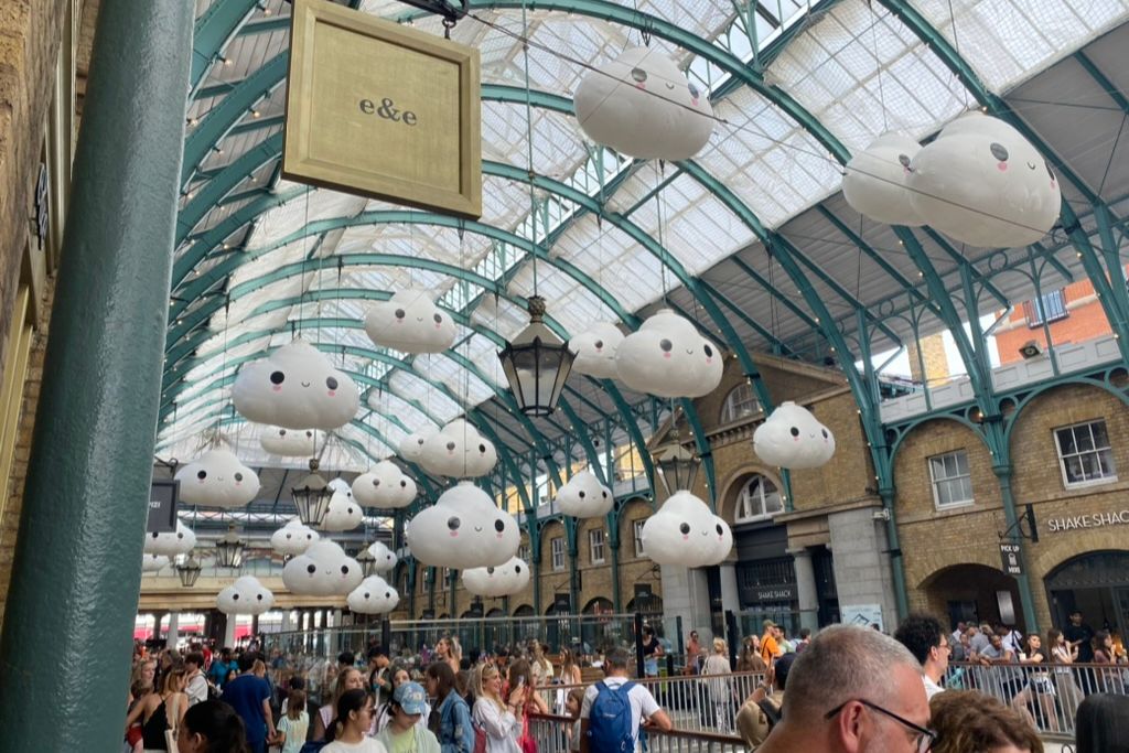 Covent Garden Piazza in London. View into the piazza with decorative clouds hanging over the shoppers.