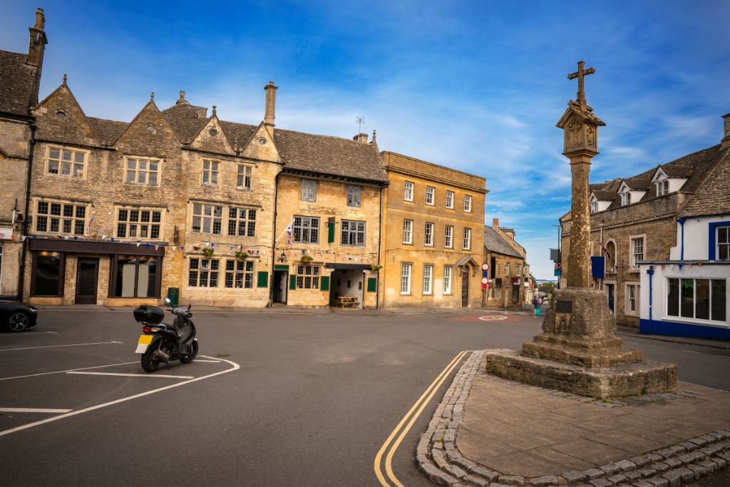 Stow-on-the-Wold market square with honey stone buildings around a historical marker.